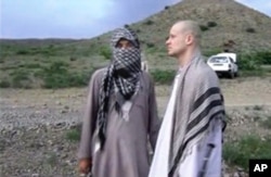 FILE: In this image taken from video obtained from Voice of Jihad website on June 4, 2014, Sgt. Bowe Bergdahl, right, stands with a Taliban fighter in eastern Afghanistan.