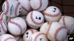 FILE- A basket of baseballs sits on a practice field, Feb. 22, 2015, during a baseball spring training workout in Bradenton, Fla. Facebook is getting deeper into the professional sports streaming game, signing a deal with Major League Baseball to show 25 afternoon games in an exclusive deal.