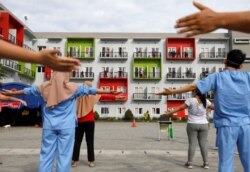 Para pasien virus corona (COVID-19) dipandu oleh para tenaga kesehatan senam pagi di balkon kamar masing-masing di pusat karantina di Tangerang, 28 Mei 2020. (Foto: Reuters)