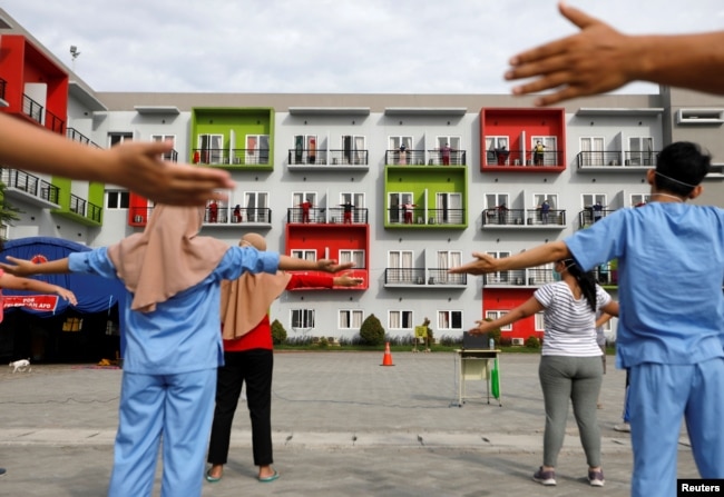 Para pasien virus corona (COVID-19) dipandu oleh para tenaga kesehatan senam pagi di balkon kamar masing-masing di pusat karantina di Tangerang, 28 Mei 2020. (Foto: Reuters)