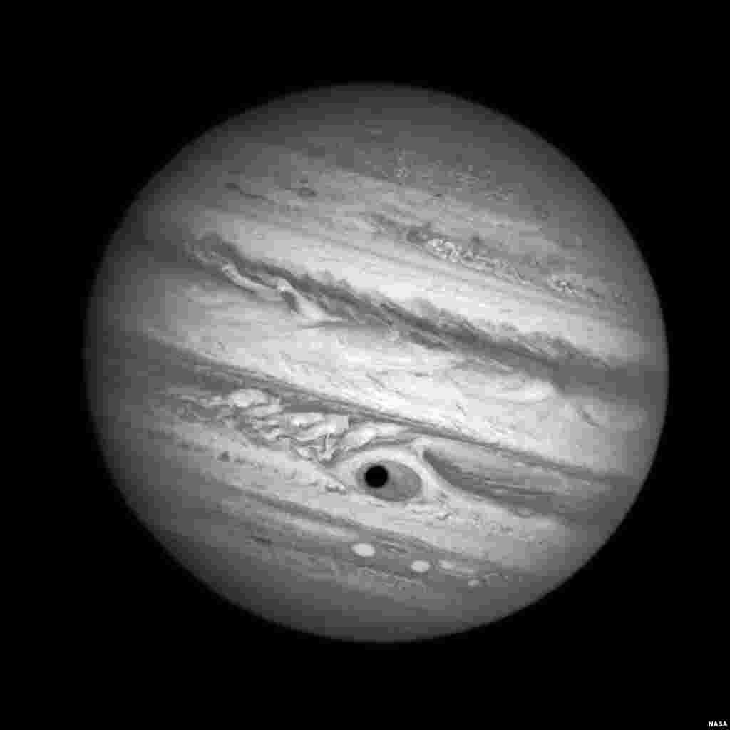 In this NASA photo released today, the Hubble telescope captures a spooky shadow on Jupiter while monitoring a Great Red Spot storm April 21, 2014. The shadow of the Jovian moon, Ganymede, swept across the storm's center, looking like a pupil in the 10,000 mile-diameter "eye."