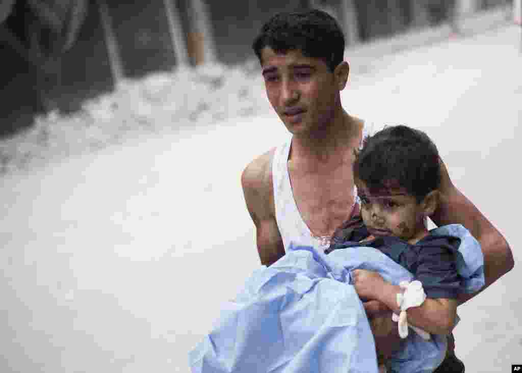 A Syrian youth holds a child wounded by Syrian Army shelling near Dar El Shifa hospital in Aleppo, Syria, October 11, 2012.