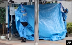 Police investigators cover the entrance of the Tsukui Yamayuri-en, a facility for the disabled where a number of people were killed and dozens injured in a knife attack, with a blue sheet in Sagamihara, outside Tokyo on July 26, 2016.