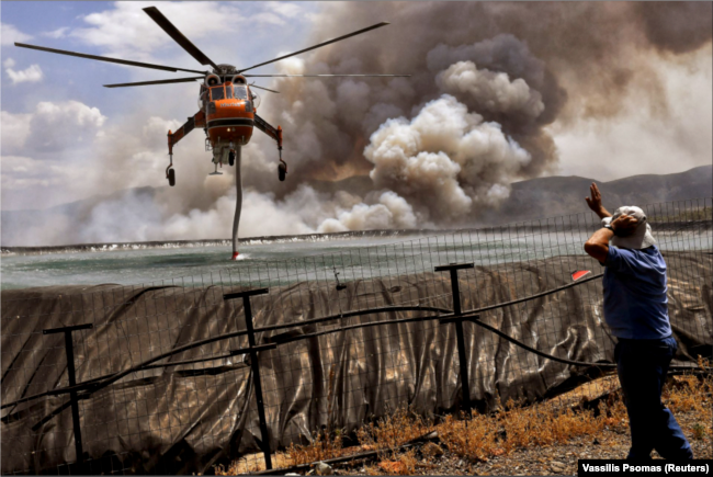 A helicopter gets filled up with water from a tank as a wildfire burns near the village of Spathovouni, near Corinth, Greece July 23, 2021. (Reuters Photo)