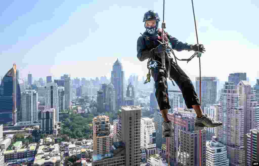 A worker scales a skyscraper to install Christmas and New Year lights in Bangkok, Thailand.