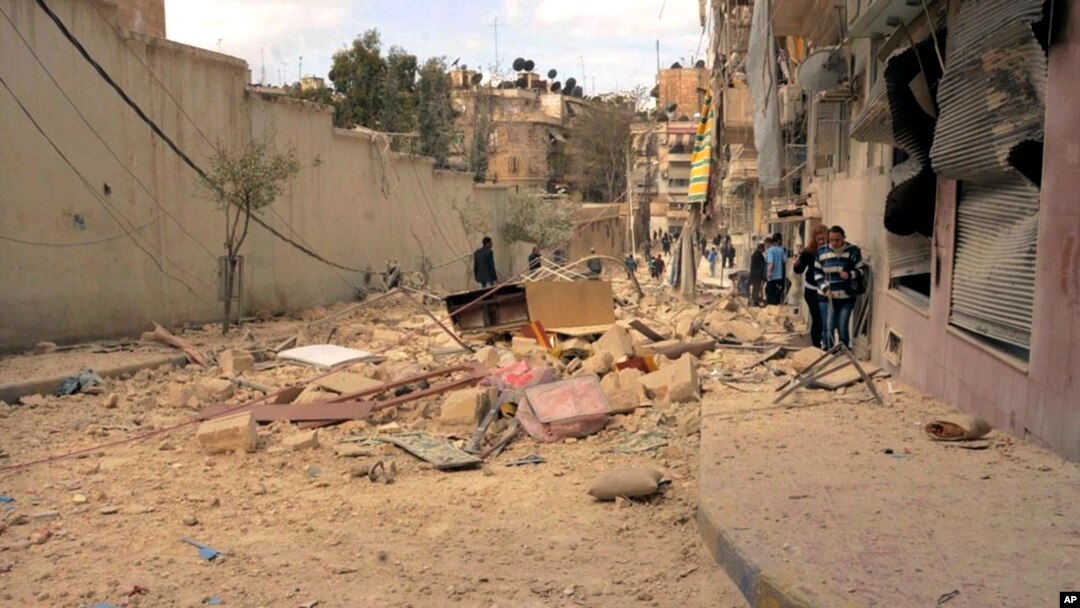 FILE - People walk amid the wreckage of damaged buildings in a street hit by shelling in Aleppo, Syria, Apr. 11, 2015.