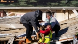Dog owner Derrick Starks, left, Chris Buchanan, center and Niki Thompson, right, both from neighboring counties, attempt to rescue Cheyenne from a tornado-damaged home in Mayfield, Ky., on Dec. 11, 2021.