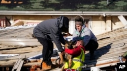 Dog owner Derrick Starks, left, Chris Buchanan, center and Niki Thompson, right, both from neighboring counties, attempt to rescue Cheyenne from a tornado-damaged home in Mayfield, Ky., on Dec. 11, 2021.