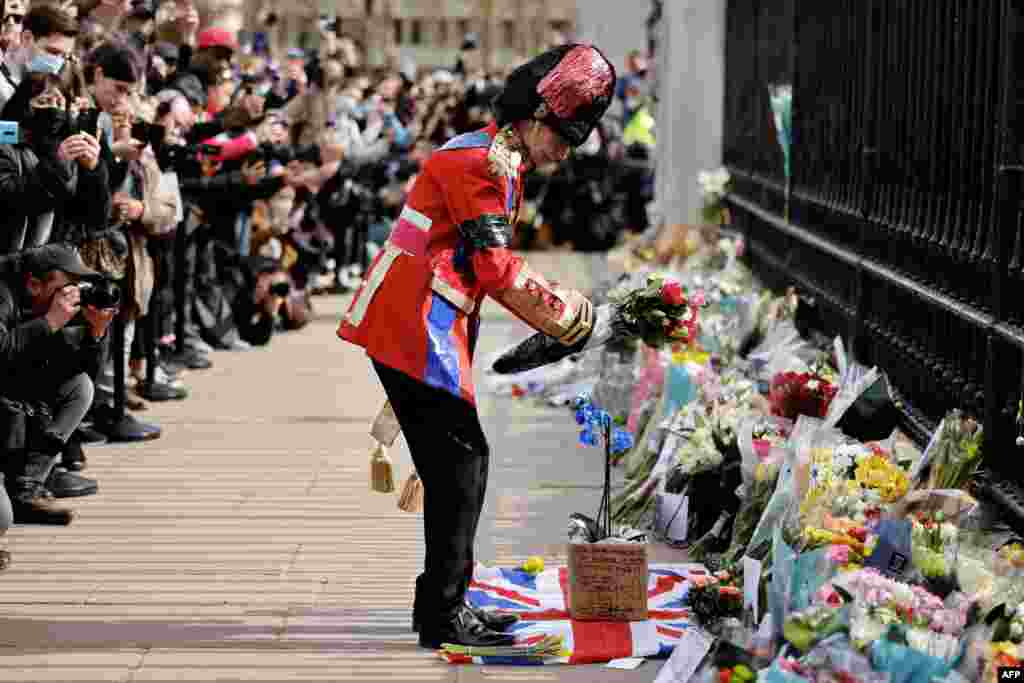 An ardent Royals fan lays a floral tribute at the front of Buckingham Palace in central London, after the announcement of the death of Britain&#39;s Prince Philip, Duke of Edinburgh. 