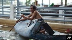A Thai man on a mattress paddles along the Chao Phraya River which runs through Bangkok, Thailand, Nov 03, 2011.
