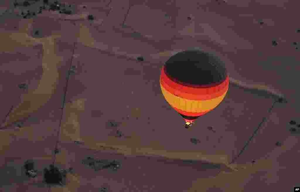 Before the sunrise, the captain of &quot;Bar&quot; hot air balloon starts the flame throwers to fill up the one of the world&#39;s largest balloon, over a camel farm in the Margham desert southeast of Dubai, United Arab Emirates. 