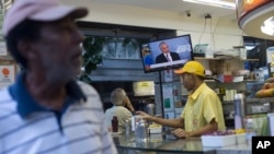 Seorang pelanggan menonton pernyataan singkat Presiden Brazil, Michel Temer, yang disiarkan di televisi tanggal 27 Juni 2017 di Rio de Janeiro, Brazil (foto: AP Photo/Silvia Izquierdo)