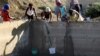 Người dân sử dụng xô và vải để lấy nước mưa đọng từ một bể xử lý nước thải ở Senekal, Nam Phi, ngày 7/1/2016.