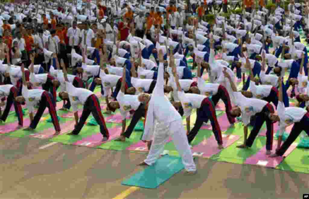 Indian Prime Minister Narendra Modi, center front, performs yoga along with thousands of Indians on Rajpath, in New Delhi, India, Sunday, June 21, 2015. Millions of yoga enthusiasts are bending their bodies in complex postures across India as they take pa
