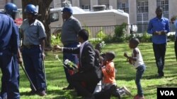 FILE: Vendors leader Sten Zvorwadza and some children attempt to give police flowers and cakes as a sign of love.