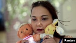 Inga Whatcott, yang diadopsi dari Rusia, berdiri di luar apartemennya di Battle Creek, Michigan sambil memegang dua boneka yang ia simpan dari panti asuhannya di Rusia, Mei 2013. (Foto:dok)