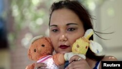 Inga Whatcott, adopted from Russia, holds two stuffed dolls she saved from her orphanage in Russia, outside her apartment in Battle Creek, Michigan, May 2013.