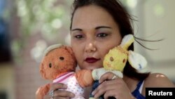 Inga Whatcott, adopted from Russia, holds two stuffed dolls she saved from her orphanage in Russia, outside her apartment in Battle Creek, Michigan, May 2013.