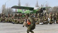 A Russian paratrooper walks as other wait to be load into a plane for airborne drills during maneuvers in Taganrog, Russia, April 22, 2021.