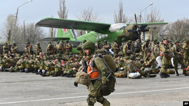 A Russian paratrooper walks as other wait to be load into a plane for airborne drills during maneuvers in Taganrog, Russia, April 22, 2021.