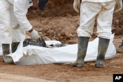 Forensic experts examine human remains at a mass grave in the village of Tomasica, near the Bosnian town of Prijedor, Oct. 31, 2013. Exhumations are currently underway at Koricani Cliffs, a nearby site.