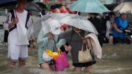 Residents, holding umbrellas amid heavy rainfall, wade through floodwaters on a road in Zhengzhou, Henan province, China July 20, 2021.