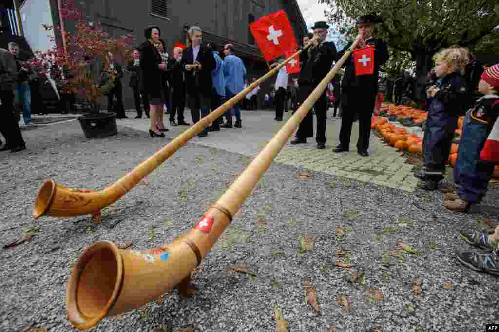 Finnish President Sauli Niinistoe (2nd L) and his wife Jenni Haukio (L) look at two men blowing into Swiss horns during a visit to a pedagogic farm in Seegraben, Switzerland.