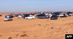 FILE - Displaced Libyans from the western city of Tawergha wait by their cars to enter the city, which lies about 250 kilometres east of the capital Tripoli, on Feb. 1, 2018.