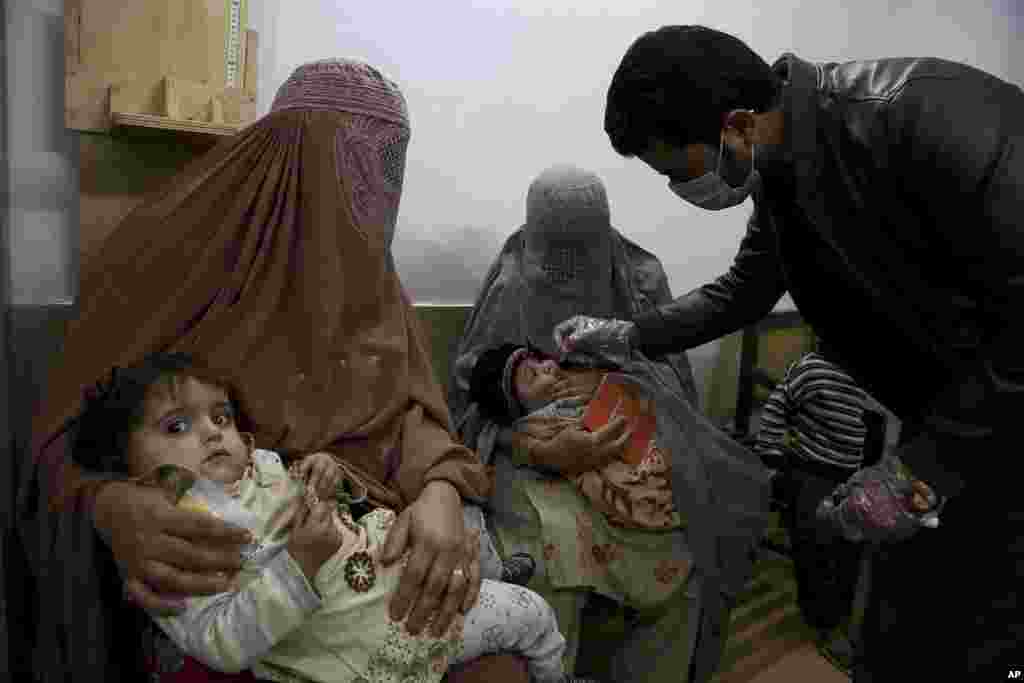 A healthcare worker administers a polio vaccine to a child at a clinic, in Peshawar, Pakistan.