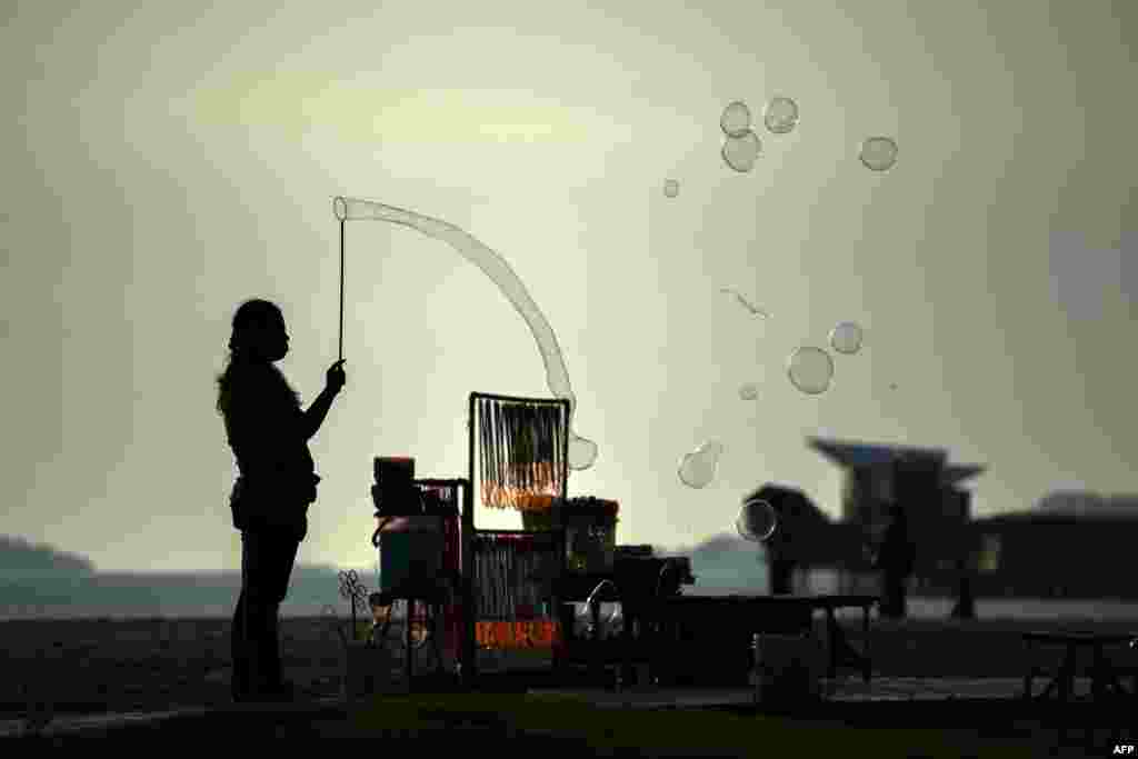 A vendor makes bubbles to attract customers at the Saujana Beach in Port Dickson, Malaysia.