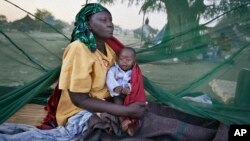 Sur cette photo prise le jeudi 2 janvier 2014 , une mère déplacée et son bébé , l'une des rares à avoir une moustiquaire , se réveiller le matin, après avoir dormi à la belle étoile, quelques-uns des milliers de personnes qui ont fui les récents combats entre forces gouvernementales et rebelles à Bor en bateau sur le Nil Blanc , dans la ville de Awerial , le Sud-Soudan . ( AP Photo / Ben Curtis )