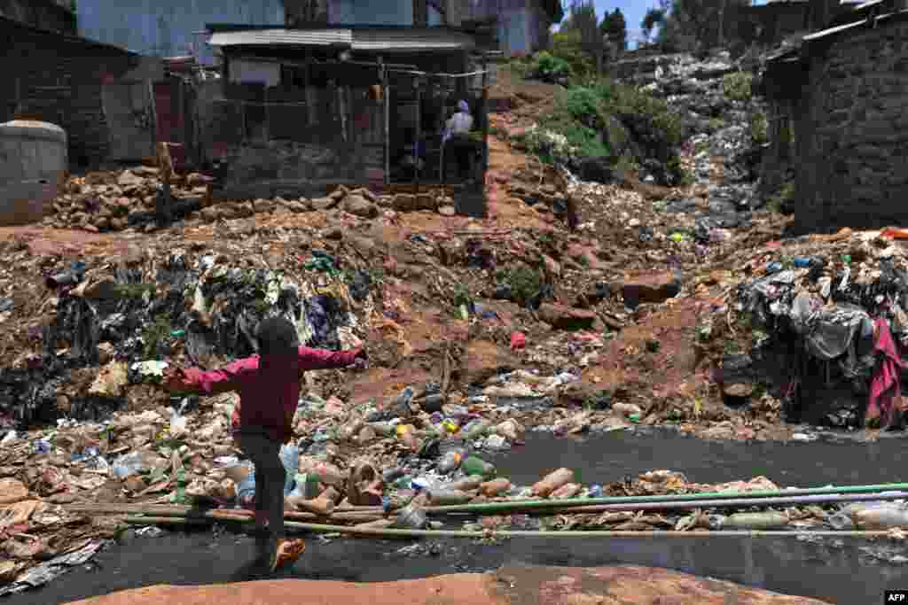 A young resident of Nairobi&#39;s Kibera slum, one of Africa&#39;s largest housing projects, crosses a heavily polluted section of the Ngong River in Kenya.