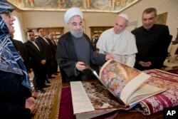 Iranian President Hassan Rouhani, left, leafs through a book he gave to Pope Francis as a gift, during their private audience at the Vatican, Jan. 26, 2016.