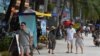 FILE - Tourists walk along a beach on Koh Rong island in Sihanoukville province on October 31, 2019. (Photo by TANG CHHIN Sothy / AFP)