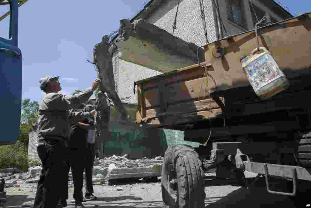 Para pekerja memindahkan lempeng beton dari sebuah sekolah yang hancur karena serangan, di Luhansk, Ukraina timur (2/7).&nbsp;(AP/Dmitry Lovetsky)