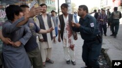 Seorang polisi mencoba menenangkan seorang warga yang marah saat terjadinya serangan terhadap masjid Syiah di Kabul, Afghanistan, 25 Agustus 2017. (AP Photo/Massoud Hossaini).