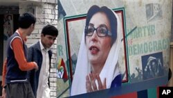 Pakistan youths walk past a portrait of former prime minister Benazir Bhutto displayed at the site where she was assassinated in Rawalpindi (File)