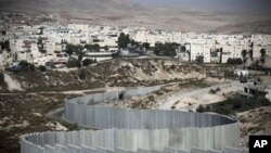 The East Jerusalem neighborhood of Pisgat Zeev is seen behind a section of Israel's separation barrier, 15 Oct 2010