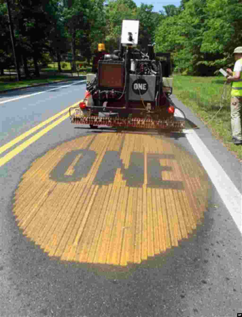 Greg Valtus, a member of the group ONE, uses a trailer mounted strayer to paint the groups logo onto Route 77 in Thurmont, Md. on Wednesday, May 16, 2012. The group, which raises awareness of worldwide poverty, used water soluble paint to spray hundreds o