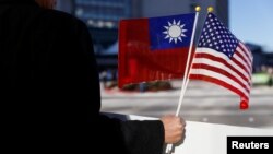 FILE - A demonstrator holds flags of Taiwan and the United States in support of Taiwanese President Tsai Ing-wen during an stopover after her visit to Latin America in Burlingame, Calif., Jan. 14, 2017.