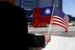 Seorang demonstran memegang bendera Taiwan dan Amerika Serikat untuk mendukung Presiden Taiwan Tsai Ing-wen saat singgah setelah kunjungannya ke Amerika Latin di Burlingame, California, AS, 14 Januari 2017. (Foto: REUTERS/Stephen Lam)