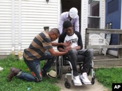 The Rev. Derrick Johnson, left, and Deacon Leonard Woods pray with gunshot victim Rayquan Briscoe behind his home in Wilmington, Del., July 25, 2017.