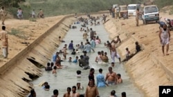 FILE - People cool themselves off in a canal as temperature reached 44 C (111 F) in Karachi, Pakistan, May 30, 2018. 