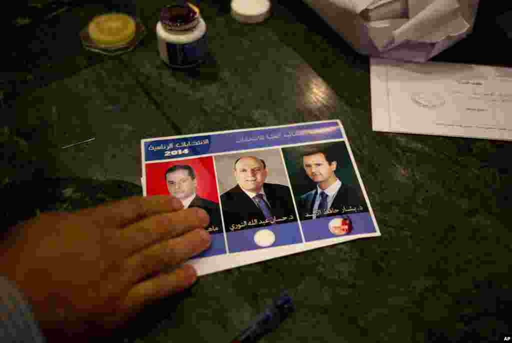 A man votes for Syria's President Bashar al-Assad on a ballot stamped with his blood, during the presidential election in Damascus, June 3, 2014.