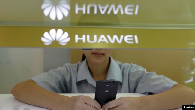 A sales assistant looks at her mobile phone as she waits for customers behind a counter at a Huawei booth in Wuhan, Hubei province, Oct. 10, 2012.