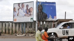 A UN vehicule passes billboards for the presidential electoral campaign on a moped in Bouake, 27 Oct 2010