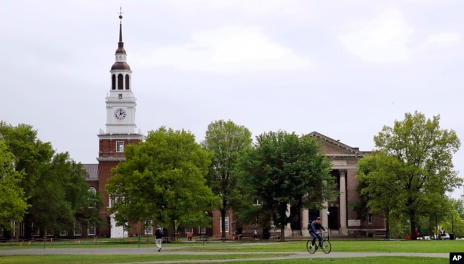 FILE- In this May 22, 2018 file photo, students cross The Green in front of the Baker-Berry Library at Dartmouth College in Hanover, N.H. (AP Photo/Charles Krupa, File)