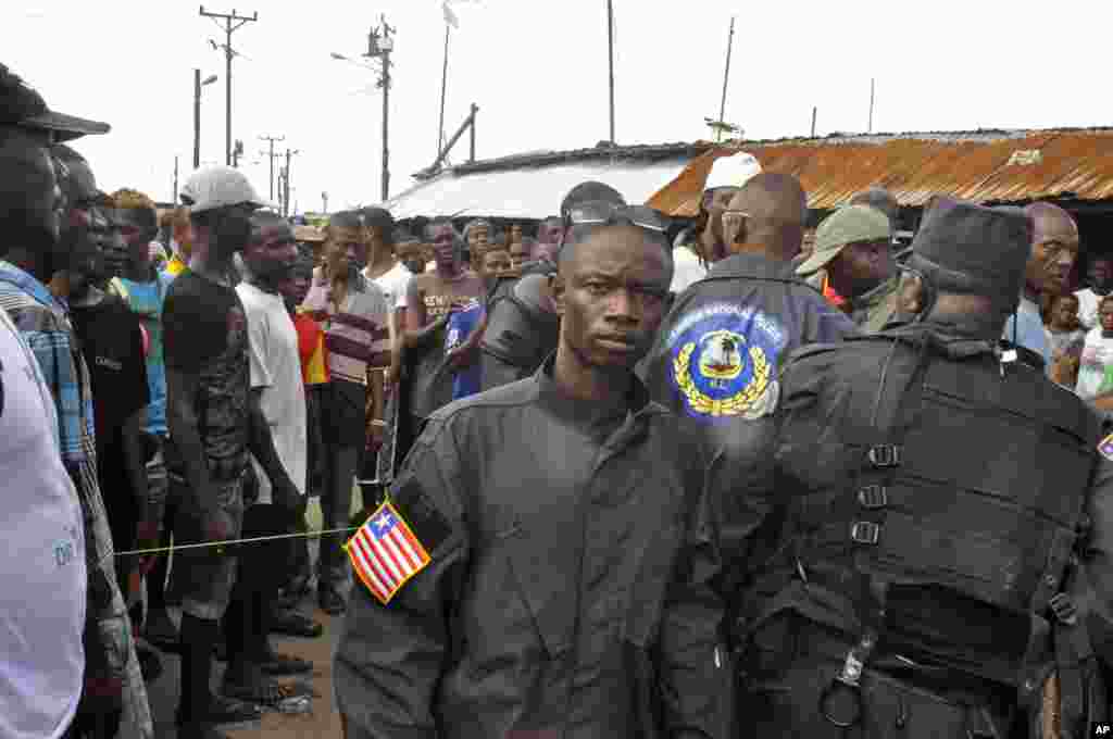 Liberian policemen (right) speak with residents of the West Point area to calm them down as they wait for a second consignment of food from the Liberian Government, at the West Point area, Monrovia, Liberia, Aug. 22, 2014.