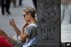 FILE - A youth checks his cell phone in Sao Paulo, Brazil.