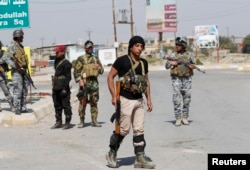 FILE - Sunni fighters who have joined Shi'ite militia groups known collectively as Hashd al-Shaabi (Popular Mobilization), allied with Iraqi forces against the Islamic State group, carry weapons as they stand guard in al-Alam Salahuddin province, March 15, 2015.